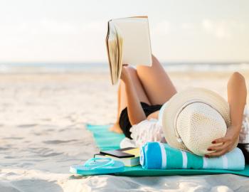 A woman reads a book on the beach